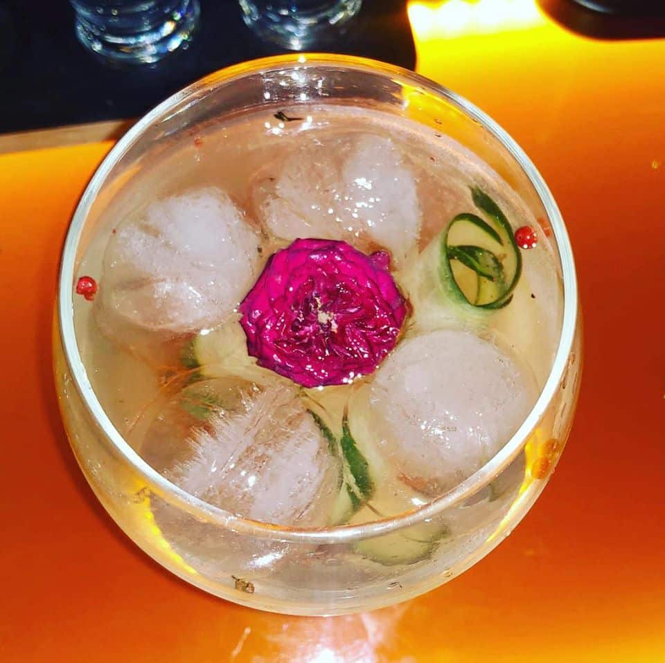 Gin cocktail with pink pepper, cucumber and edible flowers