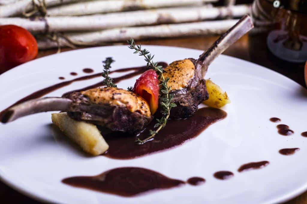 Costillitas de cordero gratinadas en costra de queso boursin y papas salteadas, confité de tomate y reducción de vino.