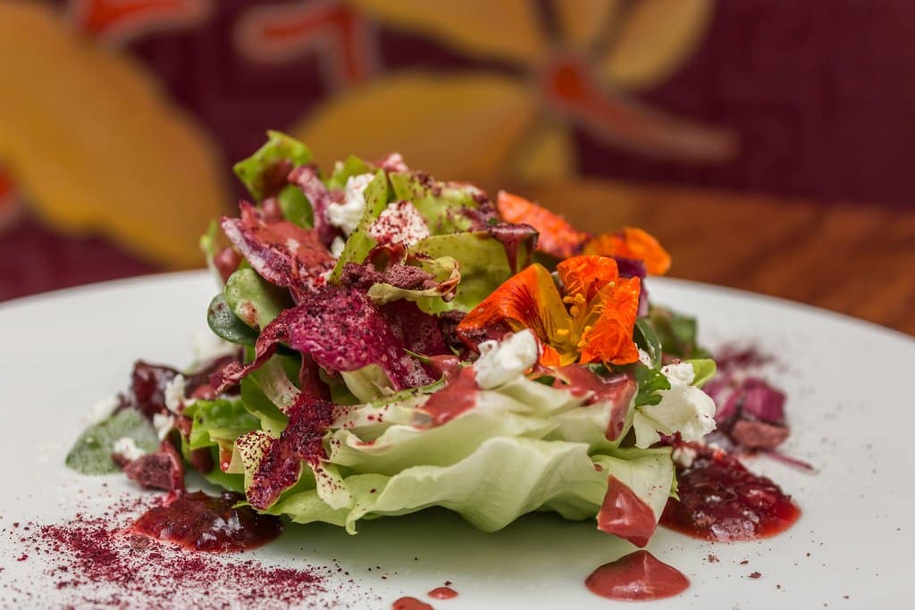 Ensalada J'Adore de lechuga mantequilla, radicchio semilla de girasol, cebollín, crocante de frambuesa, polvo remolacha, aderezo de tomate de árbol y queso fresco de cabra.