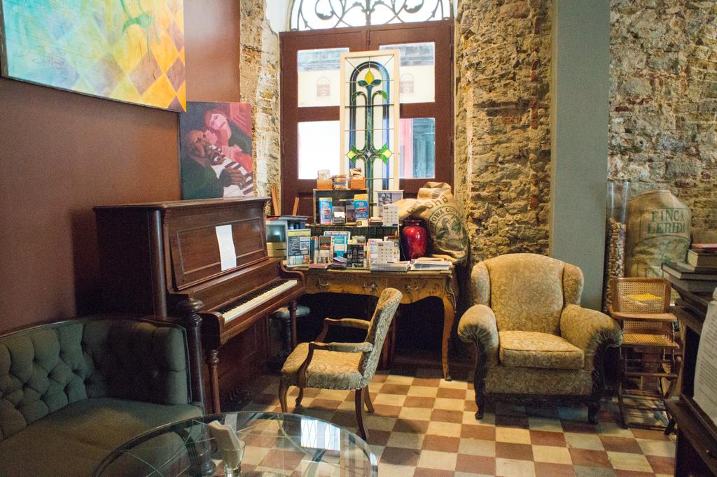 There is a piano and sofas on the corner of  Casa Sucre Coffeehouse