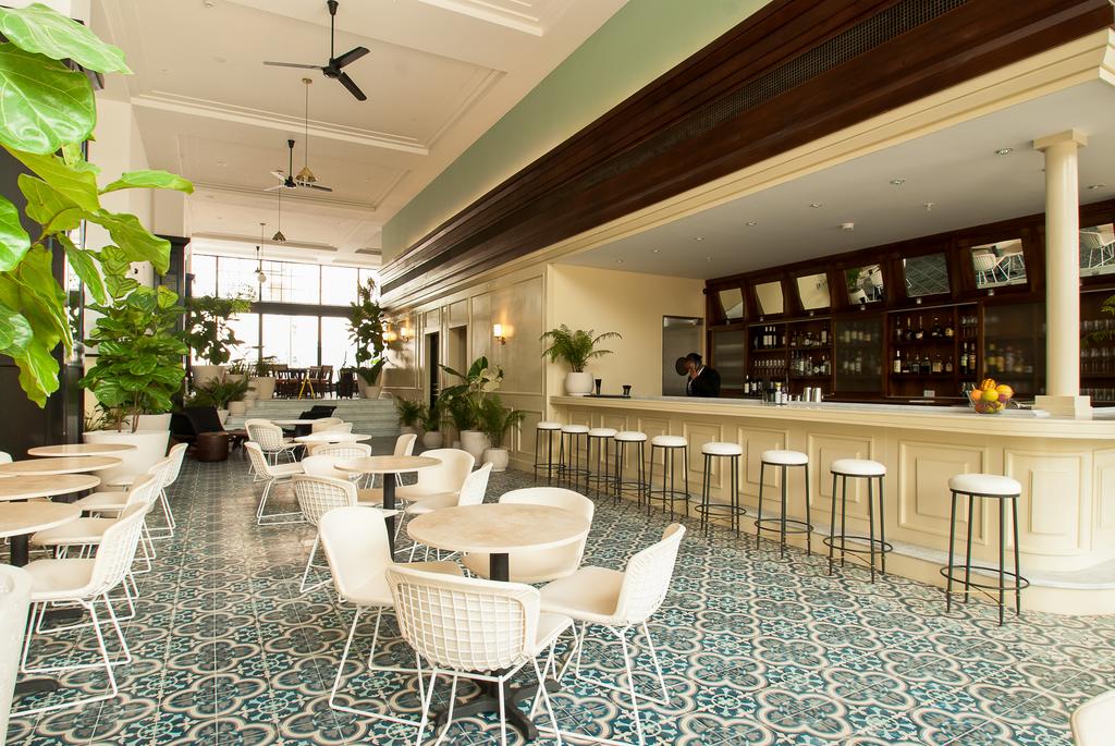 Lobby bar with stools and tables at the American Trade Hotel