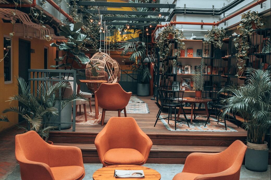 Selina Casco Viejo tiene un Bar en la Azotea, Restaurante y Espacio de Coworking Panama Casco Viejo área común en Selina Casco Viejo con muchas plantas, libros, mesas y sillas