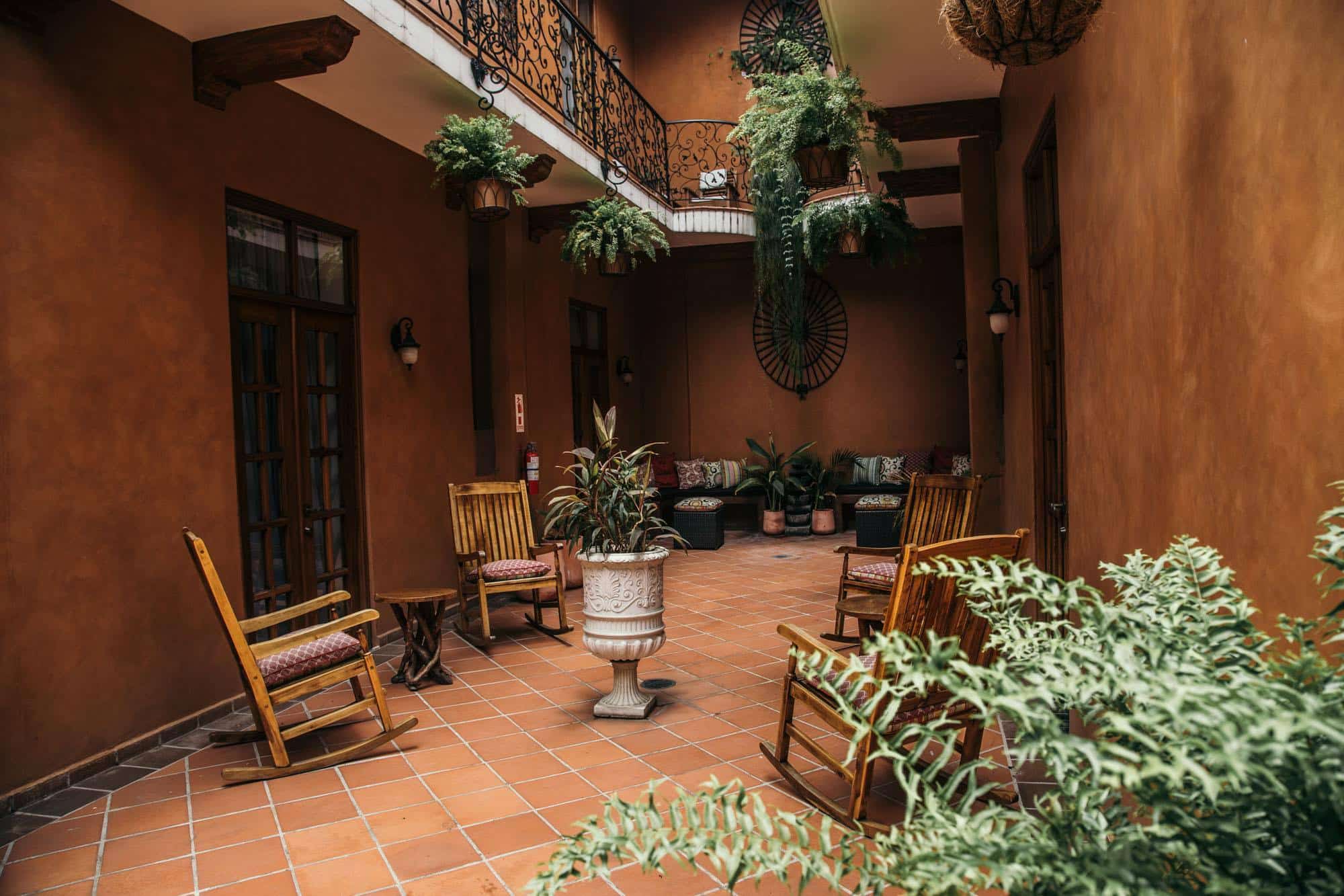 patio interno de estilo español con mecedoras y plantas en La Isabela Suites